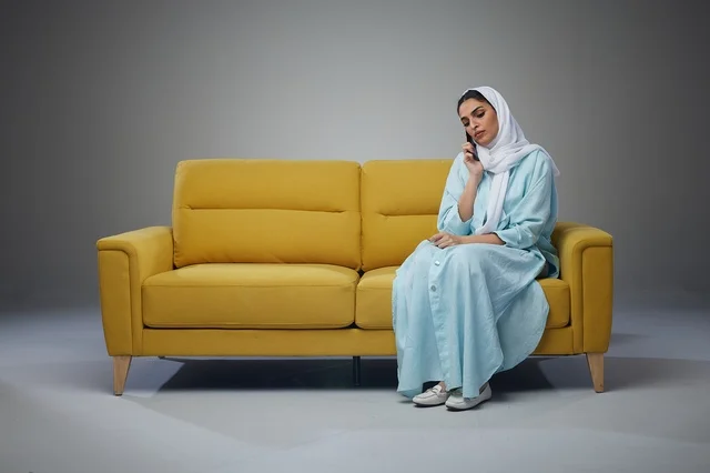 Saudi Woman Talking on Smartphone Sitting on Yellow Sofa