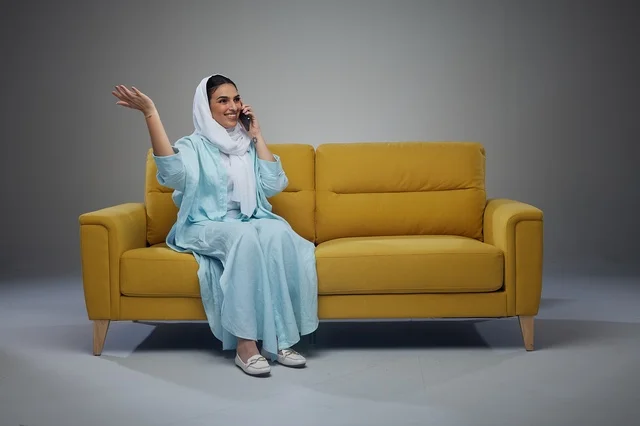 امرأة سعودية تتحدث بالهاتف على أريكة صفراء