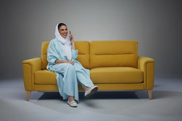 Saudi Woman Talking on Smartphone on Yellow Sofa