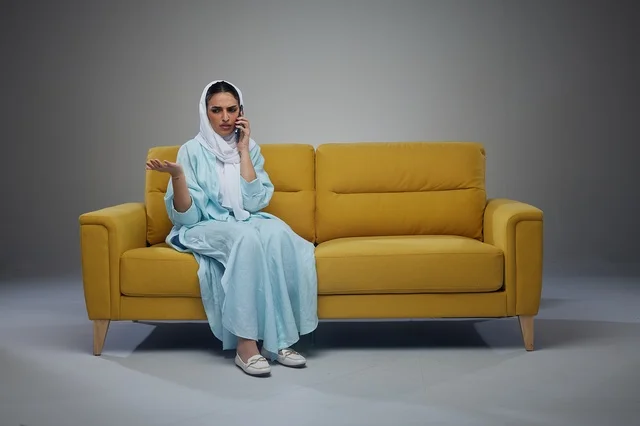 امرأة سعودية تتحدث بالهاتف على أريكة صفراء