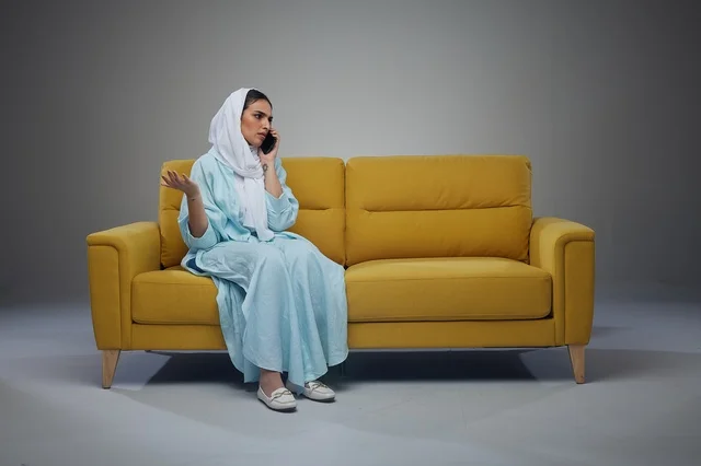 Saudi Woman Talking on Smartphone on Yellow Sofa