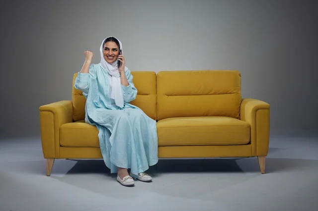 Saudi Woman on Yellow Sofa Talking on Smartphone
