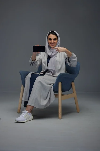 Saudi Woman Sitting in Studio Holding Smartphone