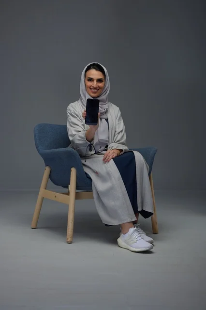 امرأة سعودية تحمل هاتفاً ذكياً في استوديو