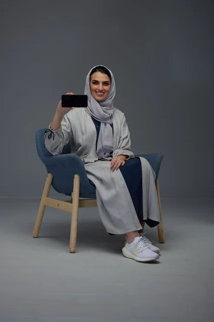 امرأة سعودية تحمل هاتفاً ذكياً في الاستوديو