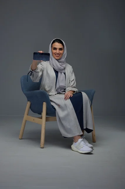 Saudi Woman Sitting in Studio Holding Smartphone