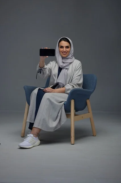 Saudi Woman Sitting and Displaying Smartphone Screen