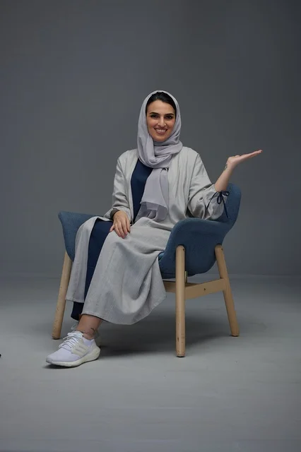 Saudi Woman in Grey Abaya Gesturing on Studio Background