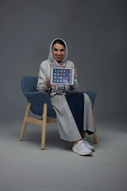 Saudi Woman Sitting Holding Tablet in Studio Background