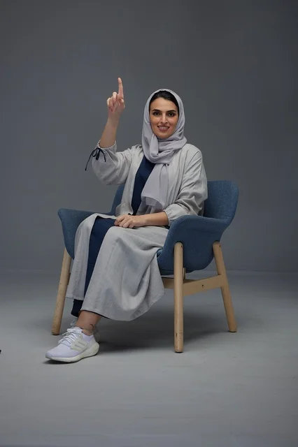 Saudi Woman Sitting in Armchair Pointing Finger Up