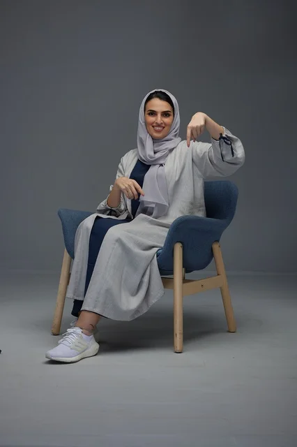 Saudi Woman Sitting and Pointing Down in Studio