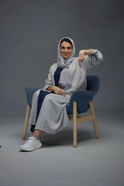 امرأة سعودية تشير للأسفل جالسة في استوديو تصوير