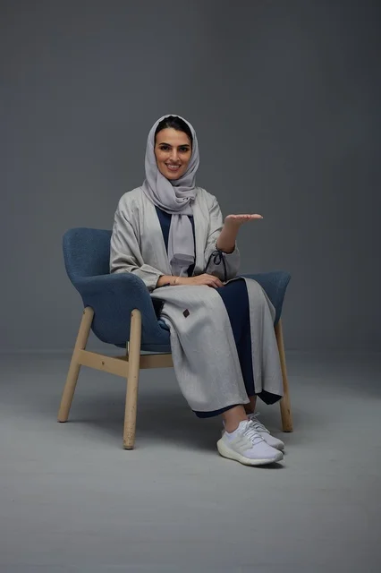 Saudi Woman in Grey Abaya Gesturing in Studio Chair