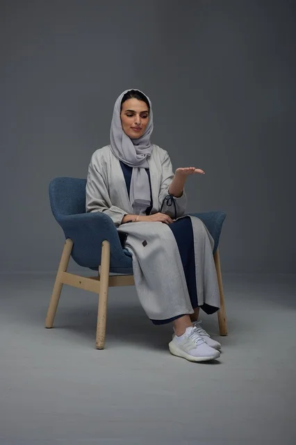 Saudi Woman Sitting in Armchair with Presentation Gesture