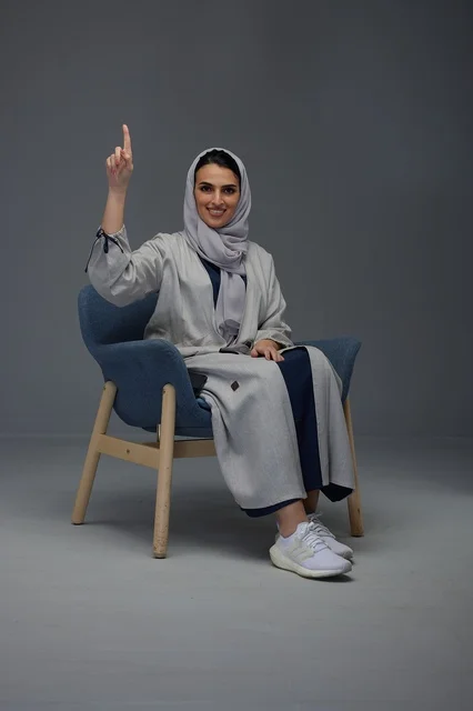 امرأة سعودية بالعباءة تشير للأعلى في استوديو تصوير