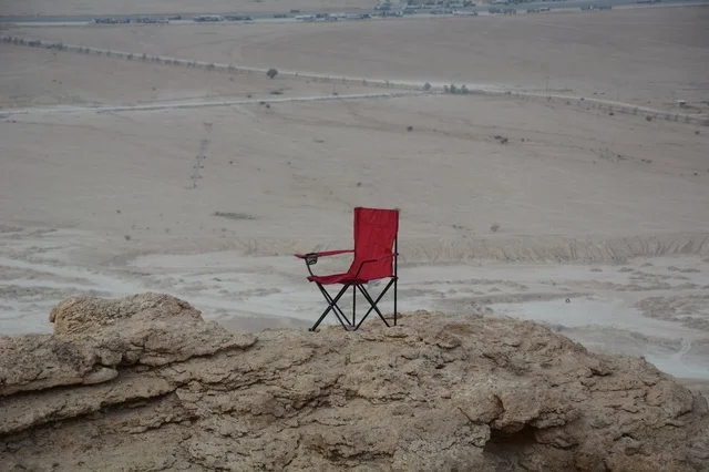 Red Folding Camping Chair on Rocky Cliff Edge Overlooking Desert