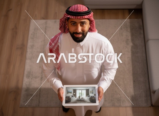رجل سعودي يمسك جهاز لوحي لعرض تصميم داخلي