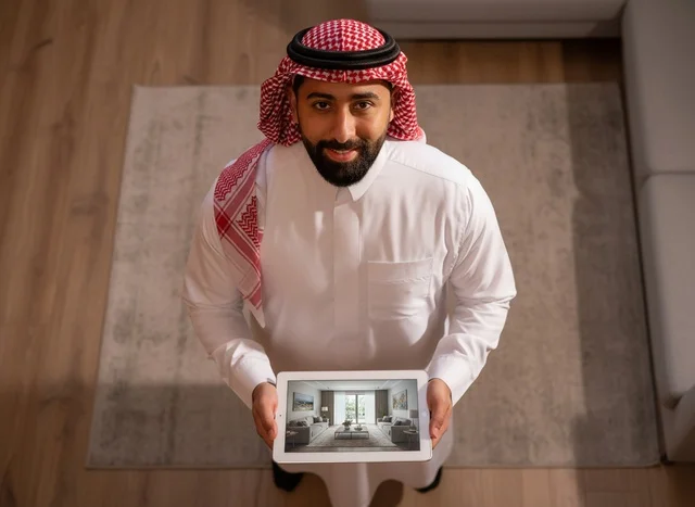 رجل سعودي يمسك جهاز لوحي لعرض تصميم داخلي