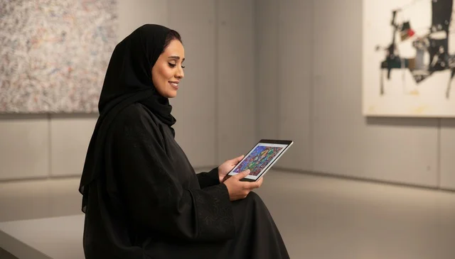 Saudi Woman Using Digital Tablet in Modern Art Gallery