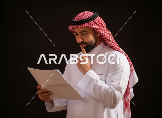 رجل سعودي بالزي التقليدي يقرأ مستنداً