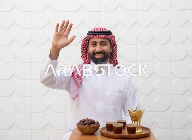 رجل سعودي يلوح مع القهوة العربية والتمر