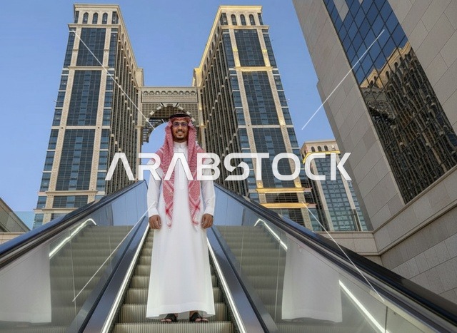 رجل سعودي بالزي التقليدي على سلم كهربائي