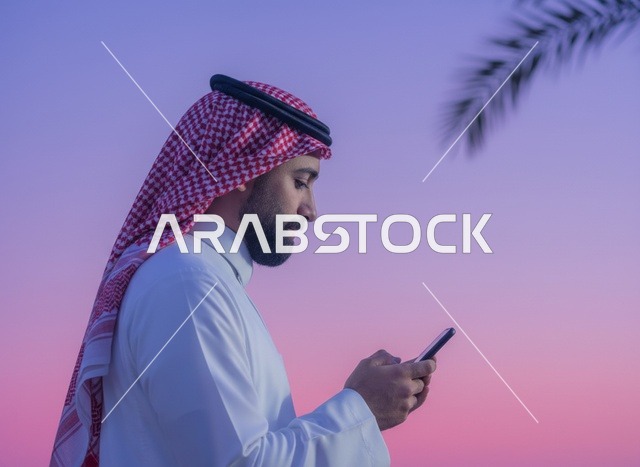 Saudi Man Using Smartphone Against Twilight Sky