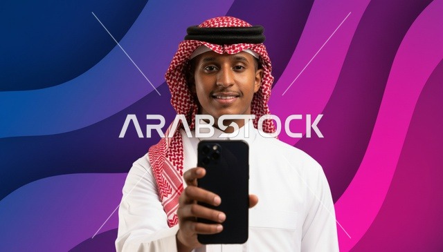 رجل سعودي يحمل هاتفاً ذكياً بخلفية ملونة