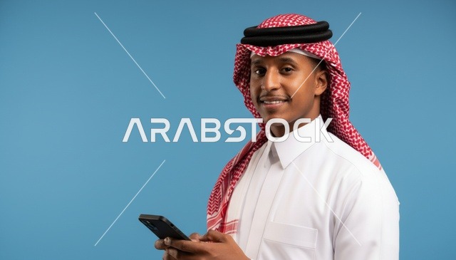 رجل سعودي يحمل هاتف ذكي بخلفية زرقاء