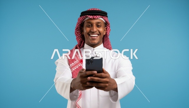 رجل سعودي مبتسم يستخدم الهاتف الذكي