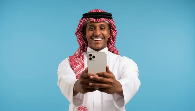 رجل سعودي بالثوب التقليدي يحمل هاتف ذكي