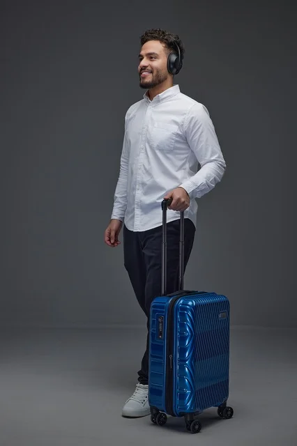Saudi Man Traveling with Blue Suitcase and Headphones