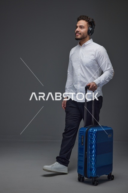 رجل سعودي يمشي مع حقيبة سفر وسماعات