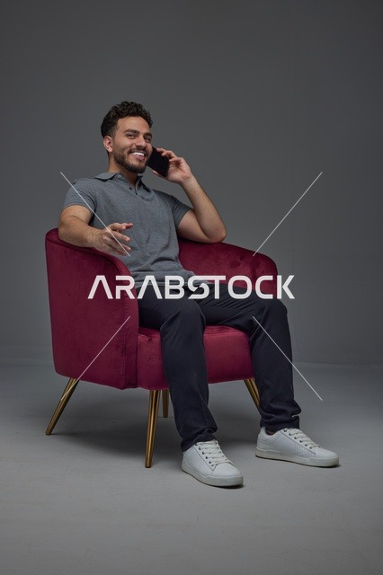رجل سعودي يتحدث بالهاتف على كرسي أحمر