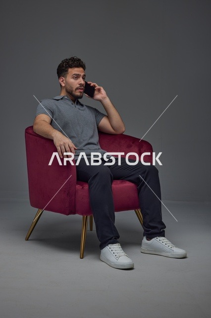 رجل عربي يتحدث بالهاتف على كرسي استوديو