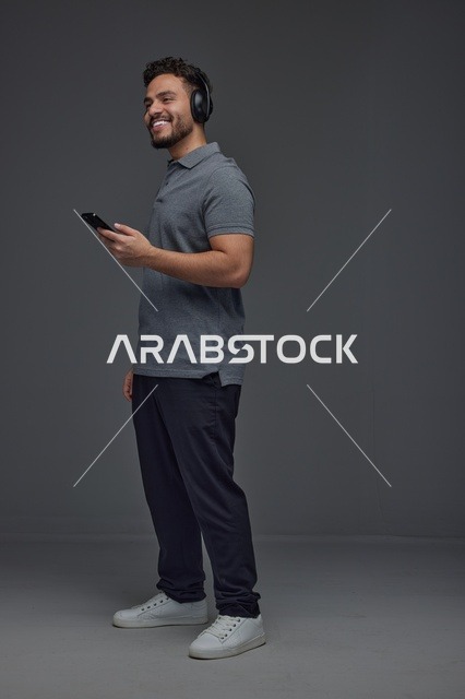 Saudi Man Using Smartphone with Headphones in Studio
