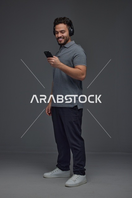 Saudi Man Using Smartphone with Headphones in Studio