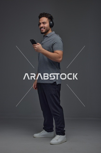 Saudi Man with Headphones Using Smartphone Studio Portrait