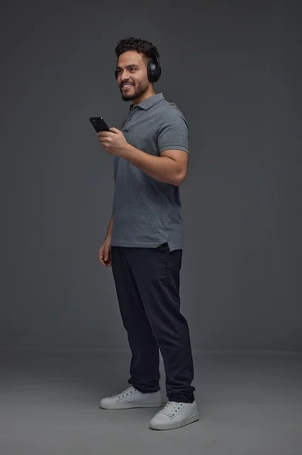 Saudi Man with Headphones Using Smartphone Studio Portrait