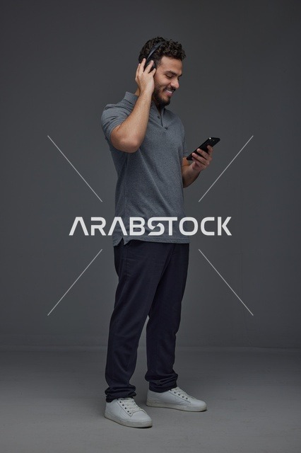 شاب سعودي يستخدم الهاتف الذكي مع سماعات الرأس