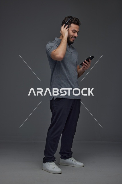 Saudi Man Using Smartphone and Headphones in Studio