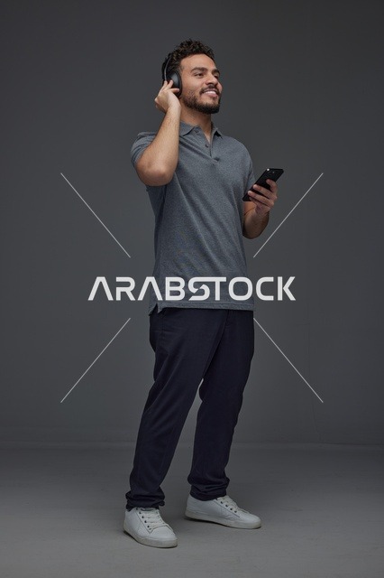 رجل سعودي يستخدم الهاتف الذكي وسماعات الرأس في الاستوديو