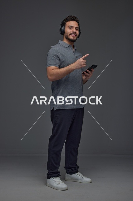 Saudi Man Using Smartphone with Headphones in Studio