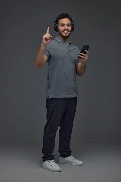 Saudi Man with Headphones Holding Smartphone Pointing Up