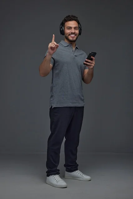 Saudi Man with Headphones and Smartphone on Grey