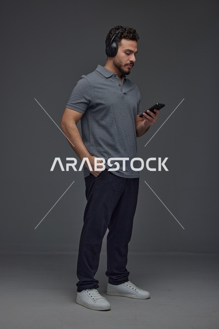 Saudi Man Using Smartphone with Headphones in Studio