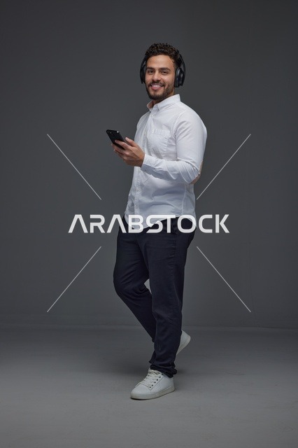 Saudi Man with Headphones Using Smartphone in Studio