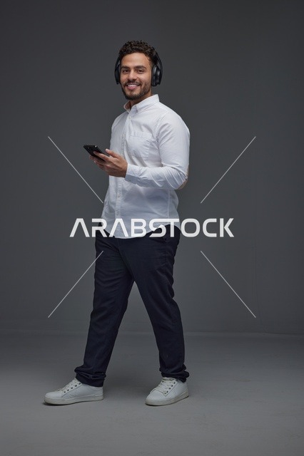 Saudi Man Using Smartphone and Headphones in Studio
