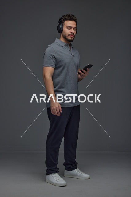 Saudi Man Using Smartphone with Headphones in Studio