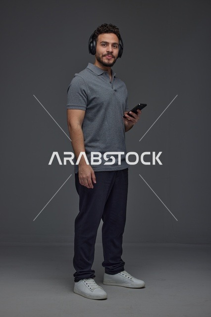 Saudi Man Using Smartphone with Wireless Headphones